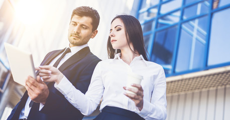 Obraz premium The business man and woman stand with a tablet on the background of the building