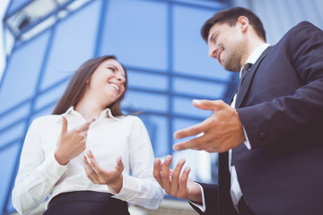 The business woman and man gesture near the modern building