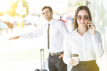 The businesswoman hold a cup of coffee and phone near the man