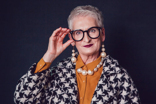 Stylish and elegant elderly woman in glasses on a black background.