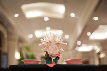 Tissue folding art in a wine cup on the black wooden table with beautiful bokeh background at the five stars hotel