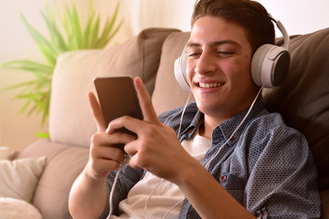 Teenager watching multimedia content with headphones sitting on couch closeup