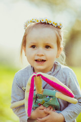 Pretty child in wreath of flowers sits on the lawn