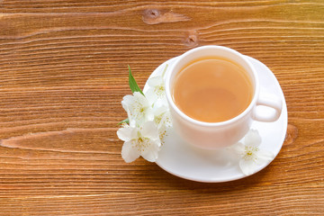 White mug of tea with jasmine on a wooden table. Top view