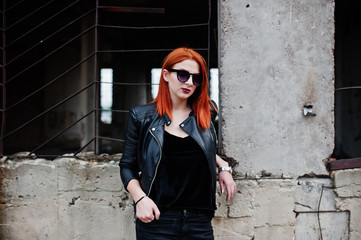 Obraz premium Red haired stylish girl in sunglasses wear in black, against abadoned place.