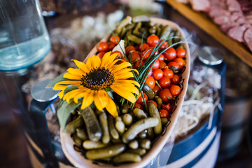 Yellow flower decorated plate with pickled tomatoes and cucumbers