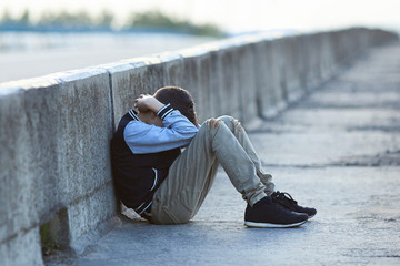 young homeless boy  crying on the bridge