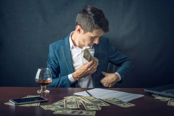 Man Businessman in suit puts money in his pocket. A bribe in the form of dollar bills. Concept of...