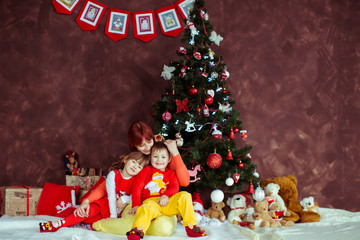 Mother sits with her children before a Christmas tree