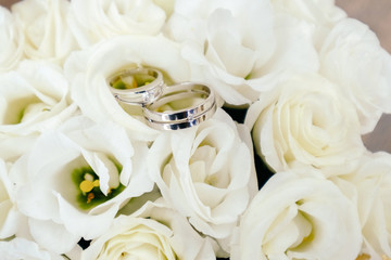 Wedding rings closeup on white roses