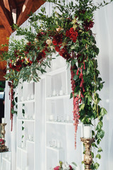 Wedding altar made of white shelves and dark red flowers