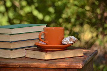The cup of tea and books on blurred background.