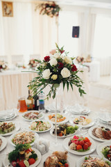 Tall vases with red and white flowers stand on the dinner tables