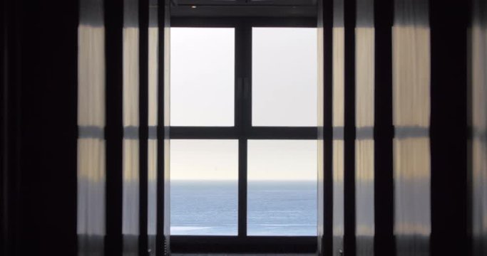 Inside the house with window overlooking the sea. Morning scene with still water and sea-gull flying by