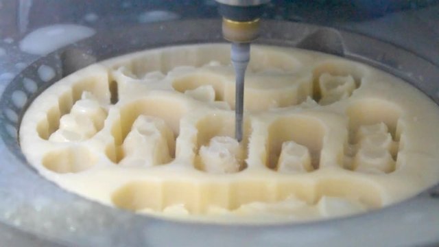 Works of the dental milling machine close-up. Processing of carving out shape of human teeth from dental milling machine. Modern medical technologies. 4.0 industrial revolution.