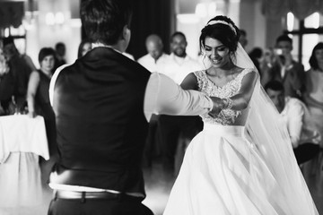 Bride and groom hold each other hands dancing in the hall