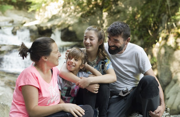 Family sitting on some rocks next to a river