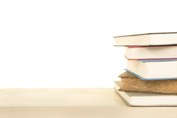Staple of 5 books lying down on a wooden shelf on a white background with space for copy