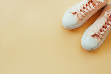 Flat lay of female sneakers on a pale peach pastel background. Place for your design, text, etc.