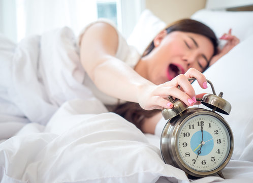 Lazy Asian Beauty Woman Wake Up Happy In The Morning, Hand Is Stopping Alarm Clock On White Bed In Bedroom