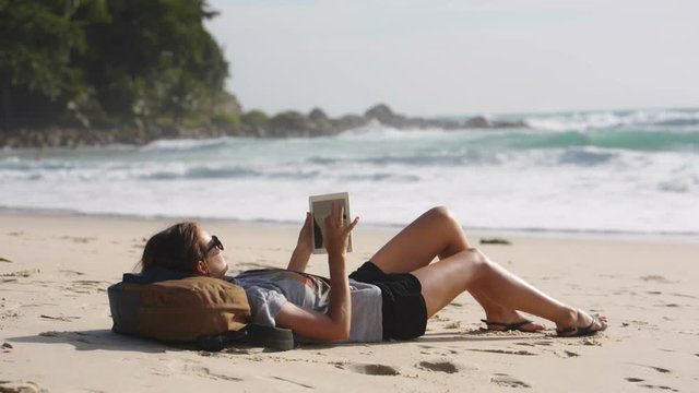 woman traveler freelancer lying with tablet PC on the beach