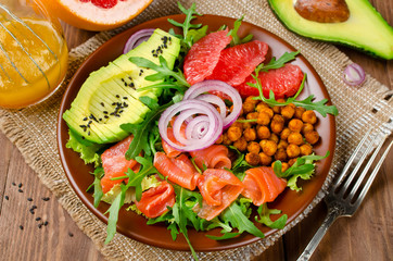 Fototapeta na wymiar Healthy salad bowl with salmon, grapefruit, spicy chickpeas, avocado, red onion and arugula