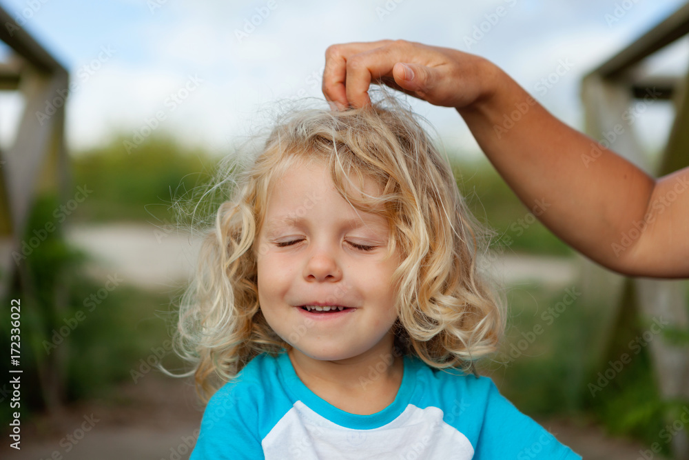 Wall mural Funny little child while his mother comb him