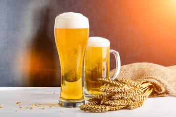 Fresh beer in two glasses against dark background in rays of the sun. Concept of Octoberfest, food and drinking