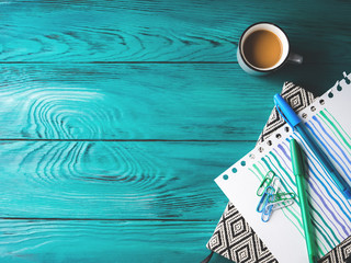 Cup of coffee, notebook and pens on dark green wooden background. Winter mood backdrop