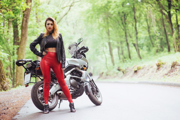 An attractive sexy girl on a sports motorbike posing outside
