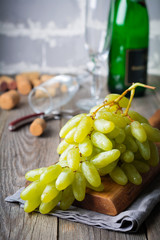 Bunch of fresh and juicy grapes, two glasses and Champagne on an old wooden background. Selective focus.