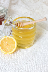 Honey in jar with honey dipper and fresh lemon on blue background