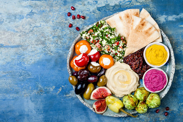 Middle Eastern meze platter with green falafel, pita, sun dried tomatoes, pumpkin and beet hummus,...