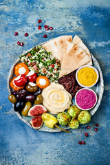 Middle Eastern meze platter with green falafel, pita, sun dried tomatoes, pumpkin and beet hummus,...