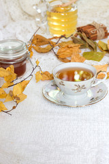 tea on romantic autumn vintage background with honey and autumn leaves on white table