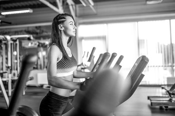 Obraz premium Young fitness woman doing cardio exercises at the gym running on a treadmill. Female runner training at the health club.