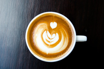 Blurred cup of coffee with beautiful Latte art on black background.