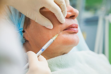 Senior woman cosmetologic injection rejuvenation skin procedure. Adult female patient wrinkle face. Beauty salon