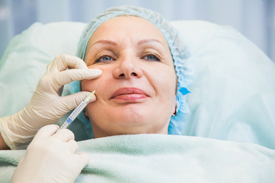 Senior woman cosmetologic injection rejuvenation skin procedure. Adult female patient wrinkle face. Beauty salon