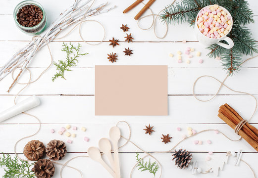 Frame Composition Of Cocoa With Marshmallow, Cinnamon, Anise Stars, Coffee Seeds, Fir Tree, Spoons And Ingredients With Clear Card On Center On White Background. Copy Space, Autumn, Kitchen Concepts.