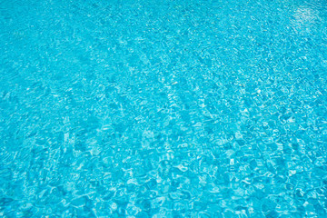 Swimming pool blue water surface with bright sun light reflection.