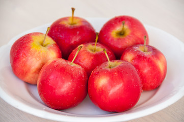 On a white plate, lot of red apples