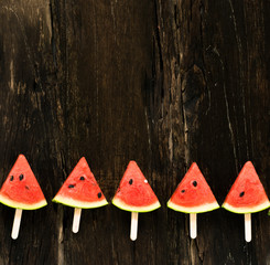the watermelon slice popsicles on a rustic wood background. copy space for designer