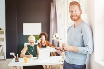 Businessman using tablet and standing near window at modern office