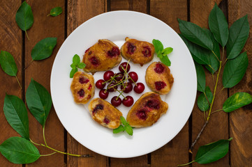 Pancakes with cherries. Wooden background. Close-up. Top view