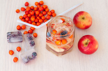 Naklejka na ściany i meble Water with sea buckthorn, forest berries and red apples