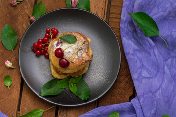 Pancakes with cherries. Wooden background. Close-up. Top view