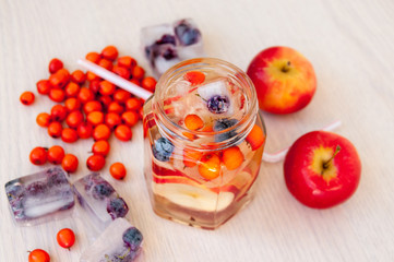 Water with sea buckthorn, forest berries and red apples