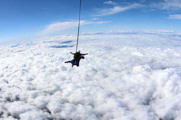 Tandem skydiving above white clouds