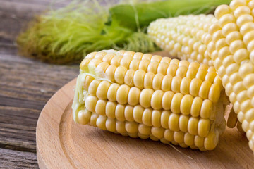Fresh corn on cobs on rustic wooden table, closeup